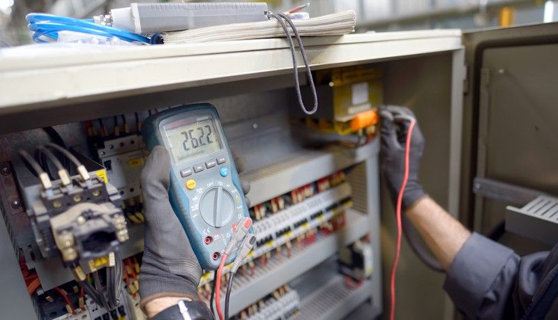 Electrical professional testing a switch board