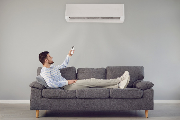 air conditioner and man sitting on grey couch