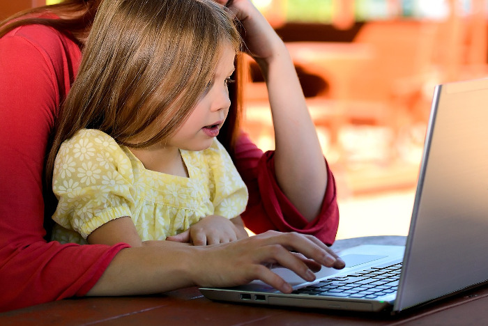 mother paying a bill on a laptop with daughter