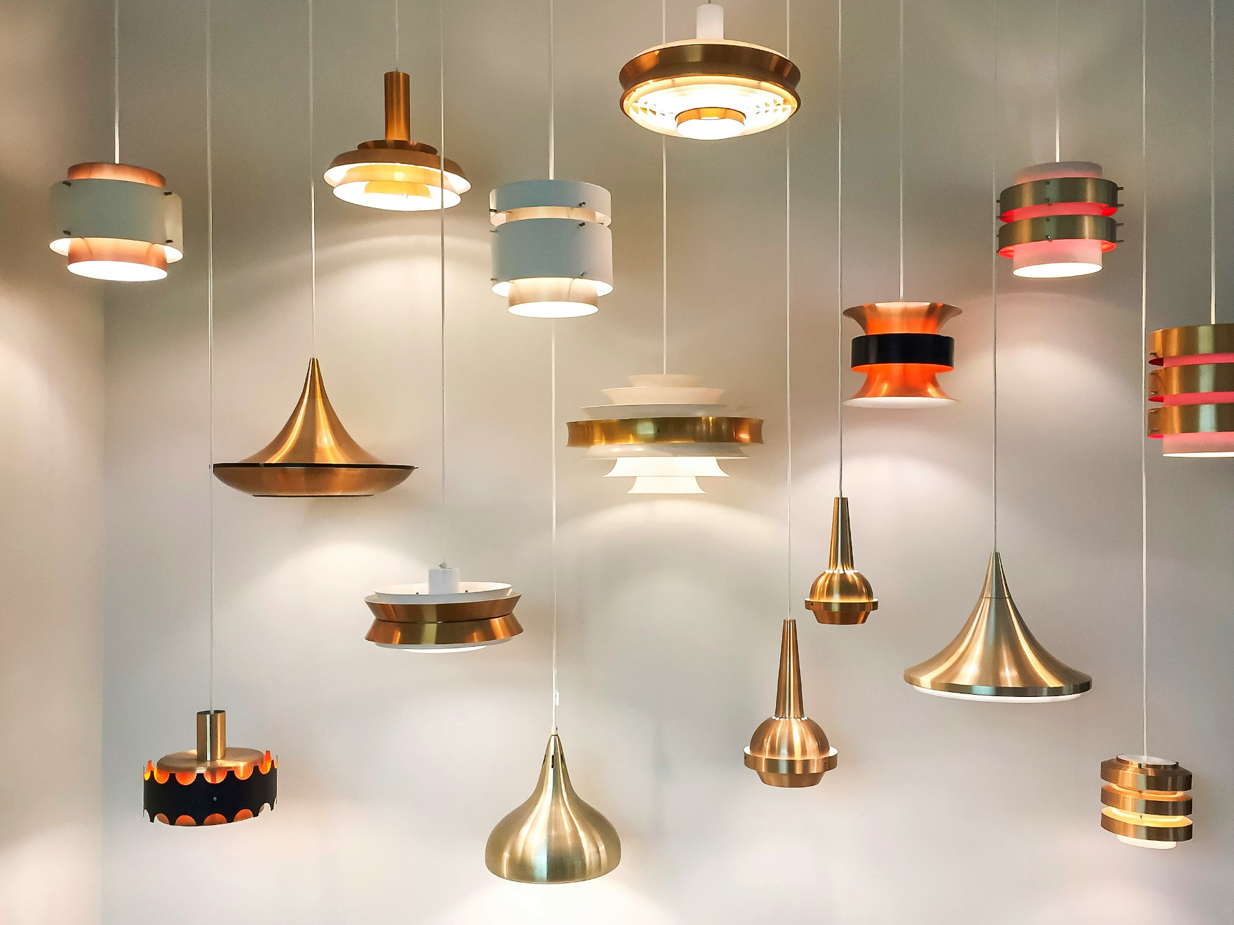 Modern pendant ceiling lights in different shapes and metallic finishes hanging on display.