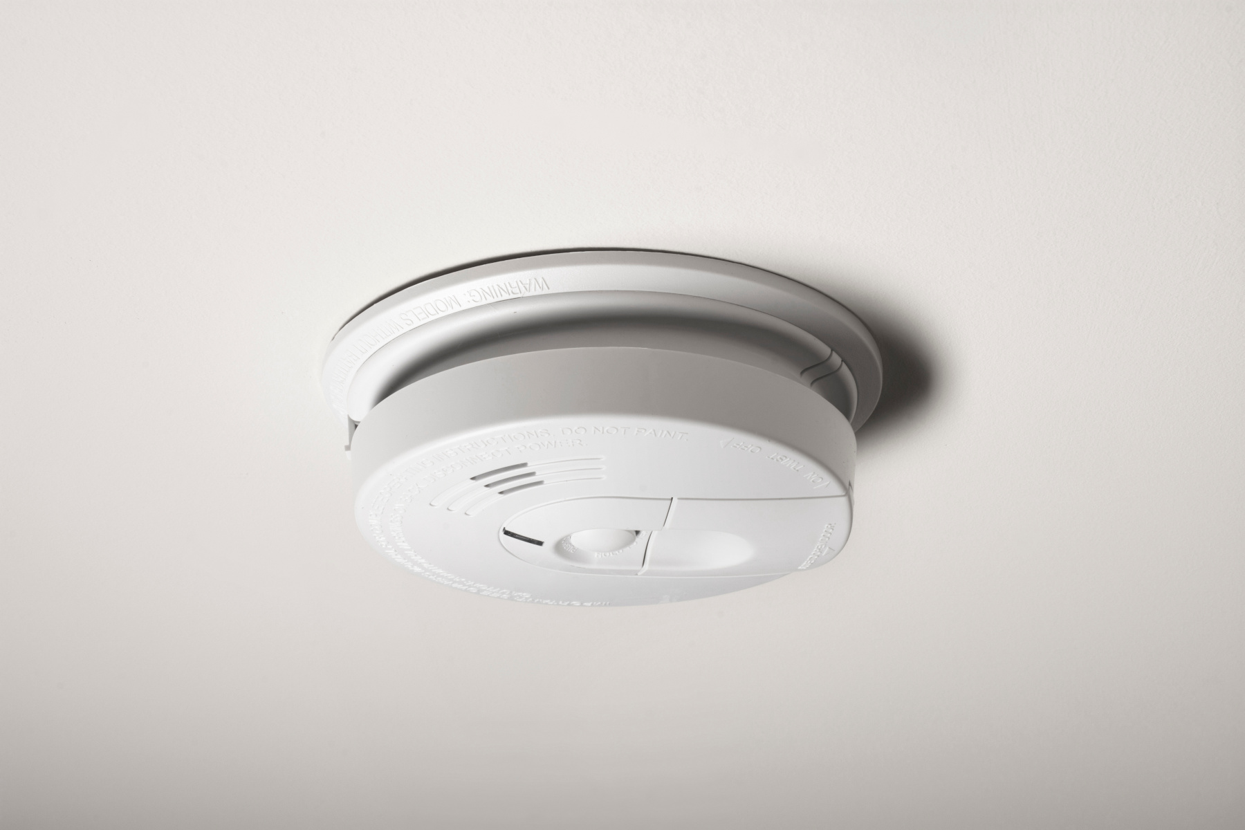 A smoke detector on the ceiling of a home.